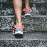 Person in orange & grey sneakers walking up stairs